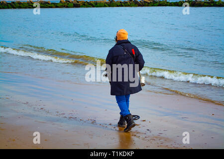 Una donna con il rivelatore di metalli cercando la spiaggia. Brooklyn, NY Coney Island Foto Stock