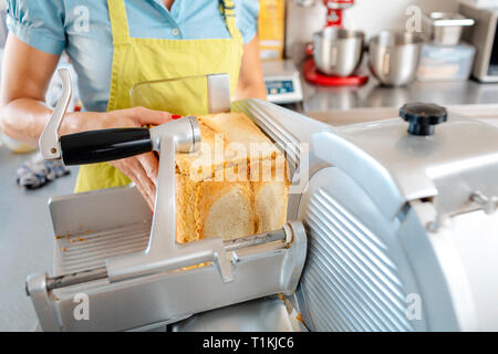 Donna mettendo a mano il pane in macchina Foto Stock