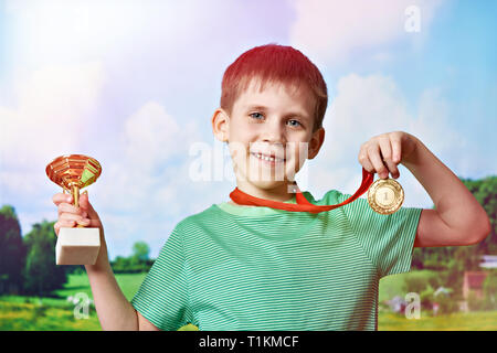 Ragazzo sportivo vincitore con la coppa e medaglia su sfondo natura Foto Stock