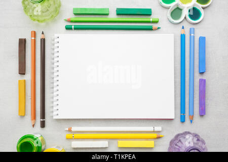 Vuota il foglio di carta di sketchbook, acquerello, acrilico e vernici a olio, matite, matite di colore pastello. Foto Stock