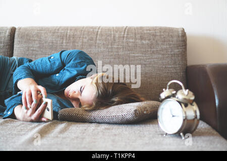 Giovane donna usando il telefono nel letto, guardando a schermo, insonnia, controllare il tempo, svegliarsi con lo smartphone, un telefono cellulare addiction - sveglia vicino Foto Stock