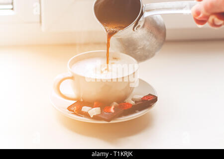 Bella ragazza fare il caffè per colazione. Donna di mano riversa fragranti caffè nella tazza. Foto Stock