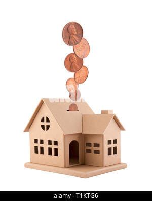 Casa di cartone con le monete che rientrano nell'alloggiamento isolato su sfondo bianco Foto Stock