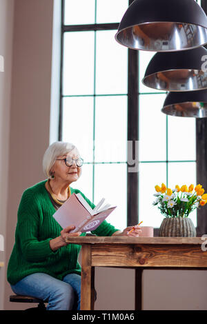 Affascinante la nonna risponde a qualcuno chiama azienda libro in mano Foto Stock
