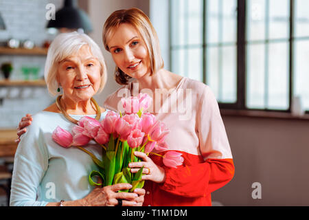 Bellissima figlia matura dando i tulipani di rugosa grigio-pelose madre Foto Stock