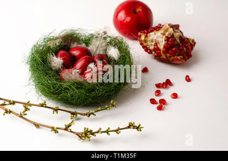 Quaglia rosso uova di Pasqua in un nido verde su uno sfondo bianco. Concetto di vacanza Foto Stock