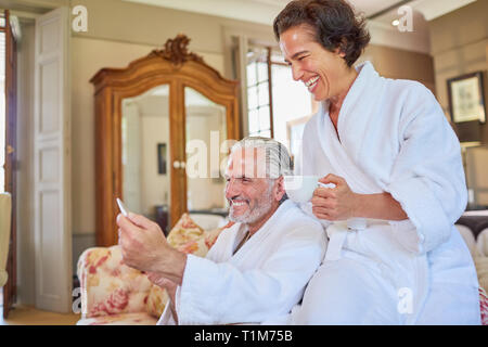 Felice Coppia matura in spa accappatoi di bere il caffè in camera di albergo Foto Stock