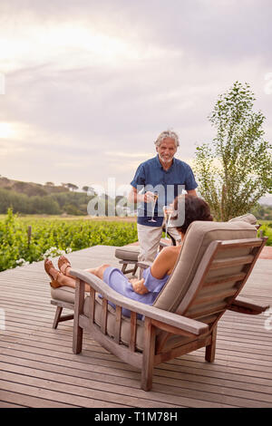 Coppia matura rilassante, tostatura flauti champagne sul patio resort Foto Stock