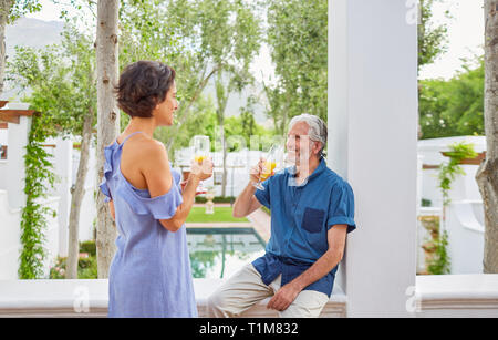 Coppia matura bere mimosas hotel sul balcone Foto Stock