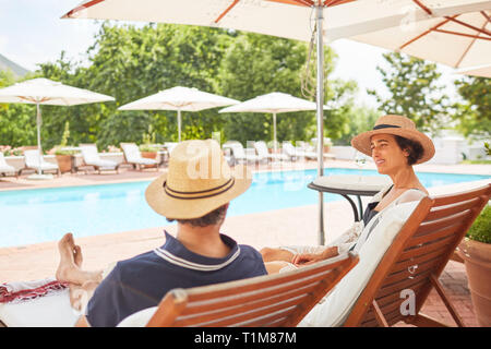 Giovane rilassarsi sulle sedie a sdraio alla piscina resort Foto Stock