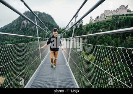 Ragazzo adolescente che attraversa il ponte sospeso Highline 179, Tirolo, Austria Foto Stock