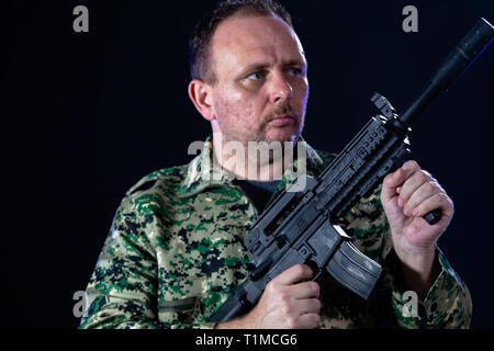 Soldato dell'esercito fatiche tenendo il fucile di assalto Foto Stock