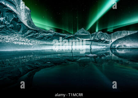 Iceberg galleggianti in Groenlandia fjord di notte con verde luci del nord. Foto Stock