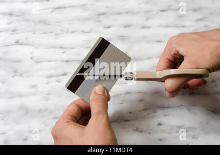 Mani femminili il taglio di carta di credito con forbici, close up Foto Stock