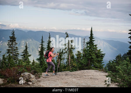 Donna escursionismo sulla cima, cane montagna, BC, Canada Foto Stock
