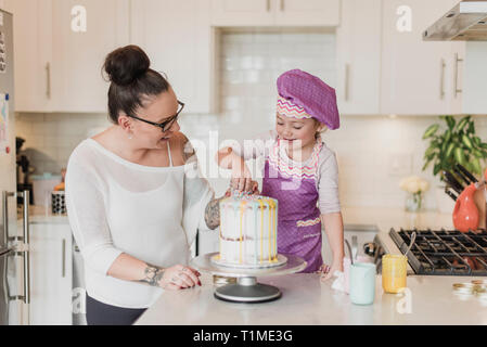 Madre e figlia decorare la torta in cucina Foto Stock
