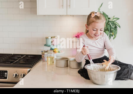 Ragazza sorridente cottura sul banco di cucina Foto Stock