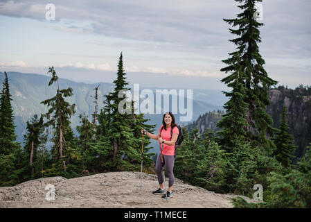 Ritratto felice giovane donna escursionismo in cima, cane montagna, BC, Canada Foto Stock