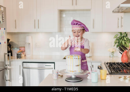 Ragazza sorridente decorare la torta in cucina Foto Stock