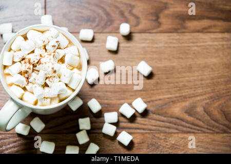 Coppa bianca di cioccolata calda con marshmallows e cannella su sfondo di legno scuro. Disposizione piatta. Vista dall'alto Foto Stock