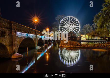 La ruota panoramica Ferris a Waterside, Stratford upon Avon, illuminato contro il cielo notturno e riflessa nel fiume Avon. Foto Stock