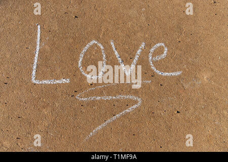 La parola amore scritta con sidewalk chalk sul cemento grigio Sfondo marciapiede Foto Stock