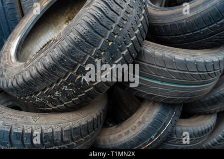 Pila casuale di auto usate di pneumatici impilati per la rivendita in un centro di distribuzione Foto Stock