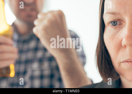 Uomo ubriaco bere birra e sostenendo con la moglie a casa, caucasico adulto giovane nella controversia interna concept a urlare contro l'altra. Foto Stock