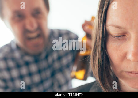 Uomo ubriaco bere birra e sostenendo con la moglie a casa, caucasico adulto giovane nella controversia interna concept a urlare contro l'altra. Foto Stock