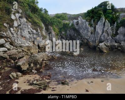 Spiaggia di Gulpiyuri, una spiaggia terrestre collegato alla costa 100m lontano dall'acqua di mare che fluisce attraverso i canali erosi in roccia calcarea, navate, Asturias, Spai Foto Stock