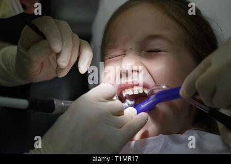 aprire la bocca di una bambina all'appuntamento del dentista. La ragazza  con bocca aperta siede nella sedia di un dentista Foto stock - Alamy