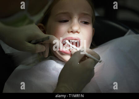 aprire la bocca di una bambina all'appuntamento del dentista. La ragazza  con bocca aperta siede nella sedia di un dentista Foto stock - Alamy