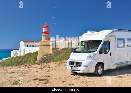 Motor home parcheggio vicino faro rosso con edificio dipinto di bianco e baby blue sky in una giornata di sole Foto Stock