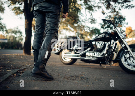 Biker in indumenti di cuoio Indumenti di cuoio va a sua trinciapaglia Foto Stock