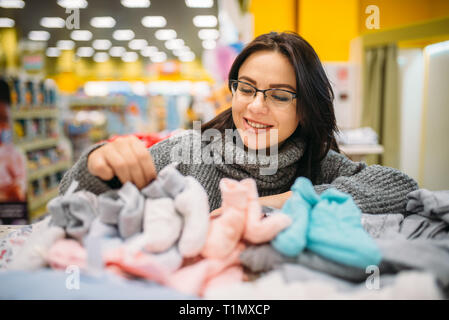 Futura madre in bicchieri compra vestiti del bambino Foto Stock