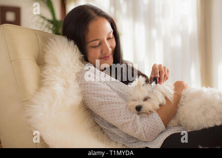 Sorridente giovane donna di spazzolatura cane dorme Foto Stock