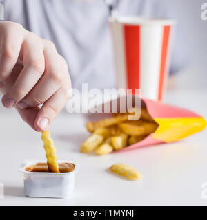 I bambini la mano schiacciate le patatine fritte in salsa di close-up, il fuoco selettivo. Foto Stock