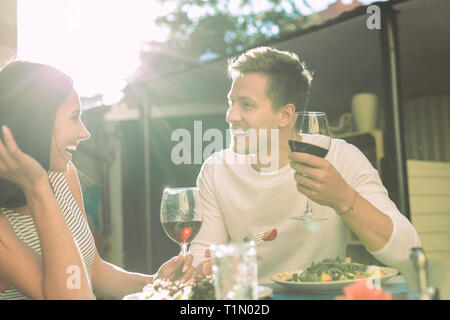 Ridere a pelo corto uomo in bianco top raccontare barzellette mentre dating Foto Stock