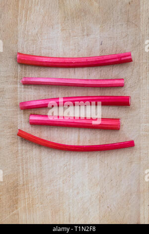 Costretto rosa stocchi di rabarbaro sul tagliere di legno Foto Stock