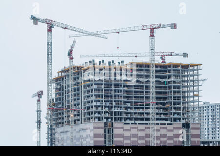 Sito in costruzione dello sfondo. Gru di sollevamento e di nuovi edifici a più piani. Background Industriale.urbano moderno edificio in costruzione con un Foto Stock