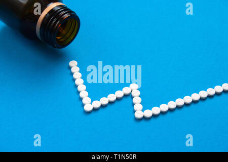 Pillole di bianco in forma di curva su sfondo blu. Prezzo del concetto di medicina Foto Stock