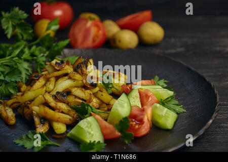 Cucinati freschi Patate fritte con cipolle e funghi close-up su una piastra in legno nero e tavola orizzontale. Foto Stock