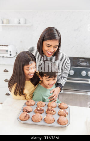 Madre e figli di cottura muffin al cioccolato in cucina Foto Stock