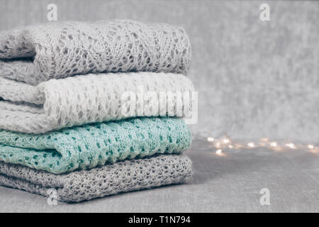 Maglia elegante color pastello maglioni a diversi modelli di maglia piegata in pila sul tessuto vellutato sfondo. Inverno e Primavera maglieria Foto Stock