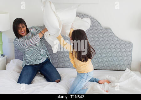 Giocoso madre e figlia godendo lotta di cuscini Foto Stock
