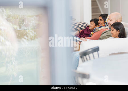 Famiglia di guardare la TV sul divano di casa Foto Stock