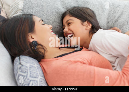 Felice, giocoso madre e figlia sul divano Foto Stock