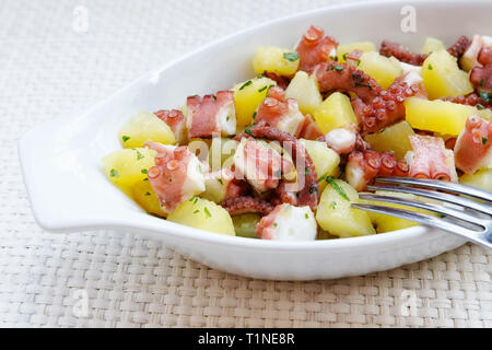Polipetti tagliati in piccoli pezzi e preparato con le patate e prezzemolo. Gustoso, pronto a mangiare. Ricetta tradizionale della cucina italiana. Foto Stock