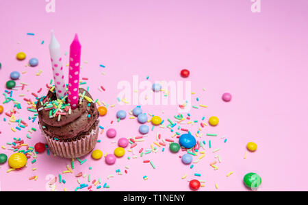 Ragazza di compleanno. Tortina di cioccolato con due candele sul rosa pastello, sfondo spazio copia. Foto Stock