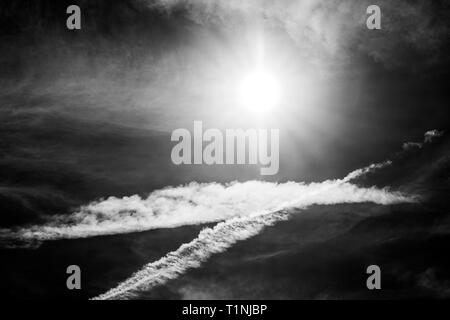 Bianco & Nero vista del jet contrails creano modelli contro il cielo blu cobalto & sun; central Colorado; USA Foto Stock